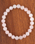 Pulsera de Cuarzo Rosa facetada de 8 mm, pieza completa sobre madera oscura