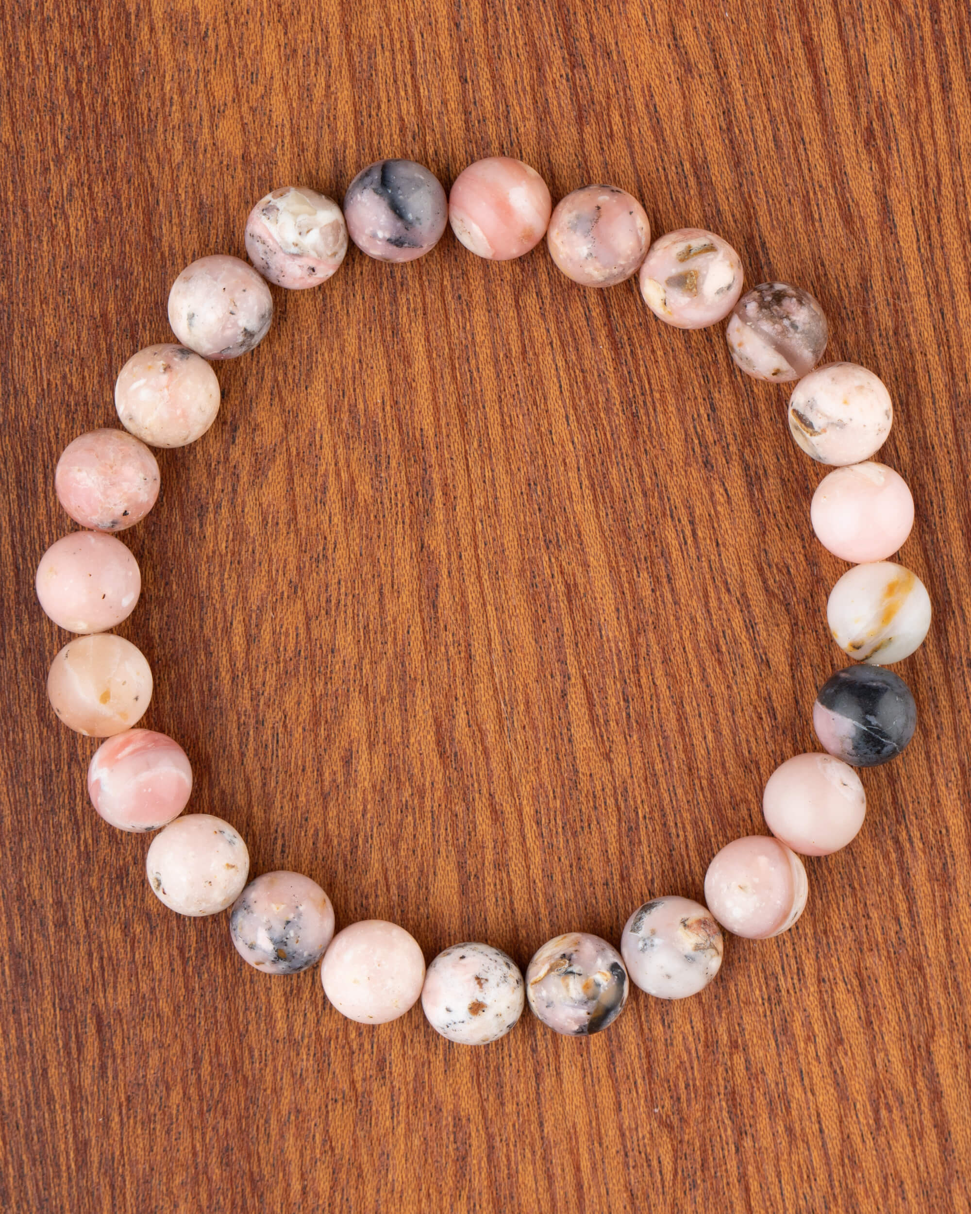 Pulsera de Ópalo Rosa, pieza completa en círculo sobre madera