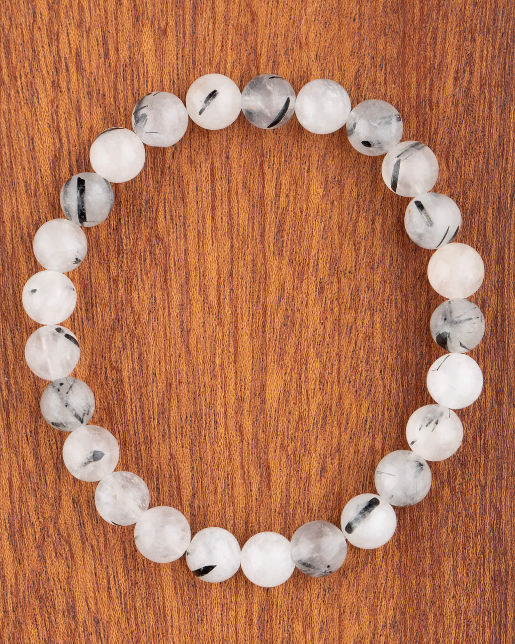 Pulsera de Cuarzo Turmalinado, pieza completa en círculo sobre madera