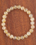 Pulsera de Cuarzo Rutilado de 8 mm, pieza completa en círculo sobre madera
