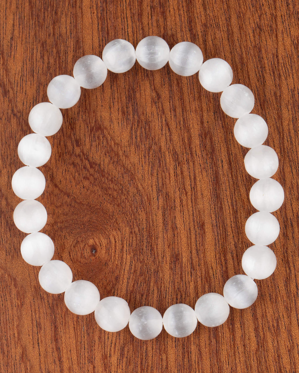 Pulsera de Selenita de 8 mm, pieza completa en círculo sobre superficie de madera