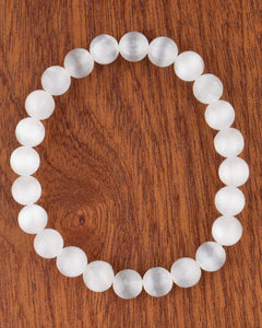 Pulsera de Selenita de 8 mm, pieza completa en círculo sobre superficie de madera