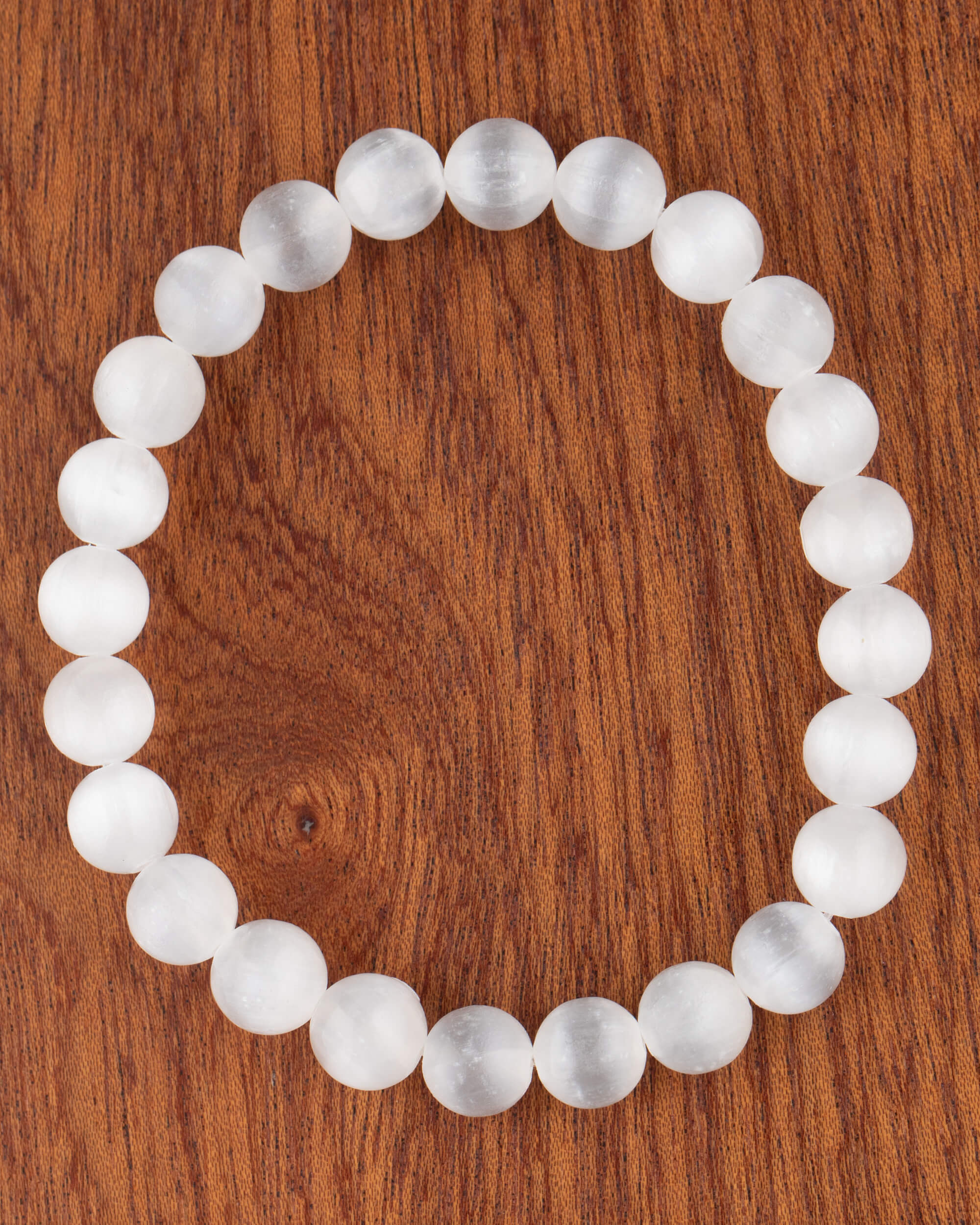 Pulsera de Selenita de 8 mm, pieza completa en círculo sobre superficie de madera