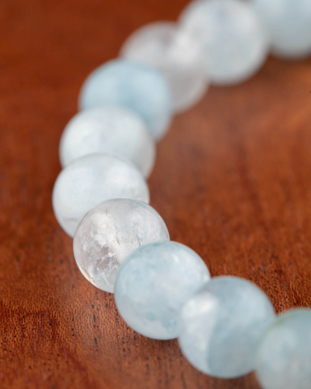 Pulsera de Aguamarina de 8 mm, vista en perspectiva sobre madera