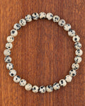 Pulsera de Jaspe Dálmata de 6 mm, pieza completa en círculo sobre madera