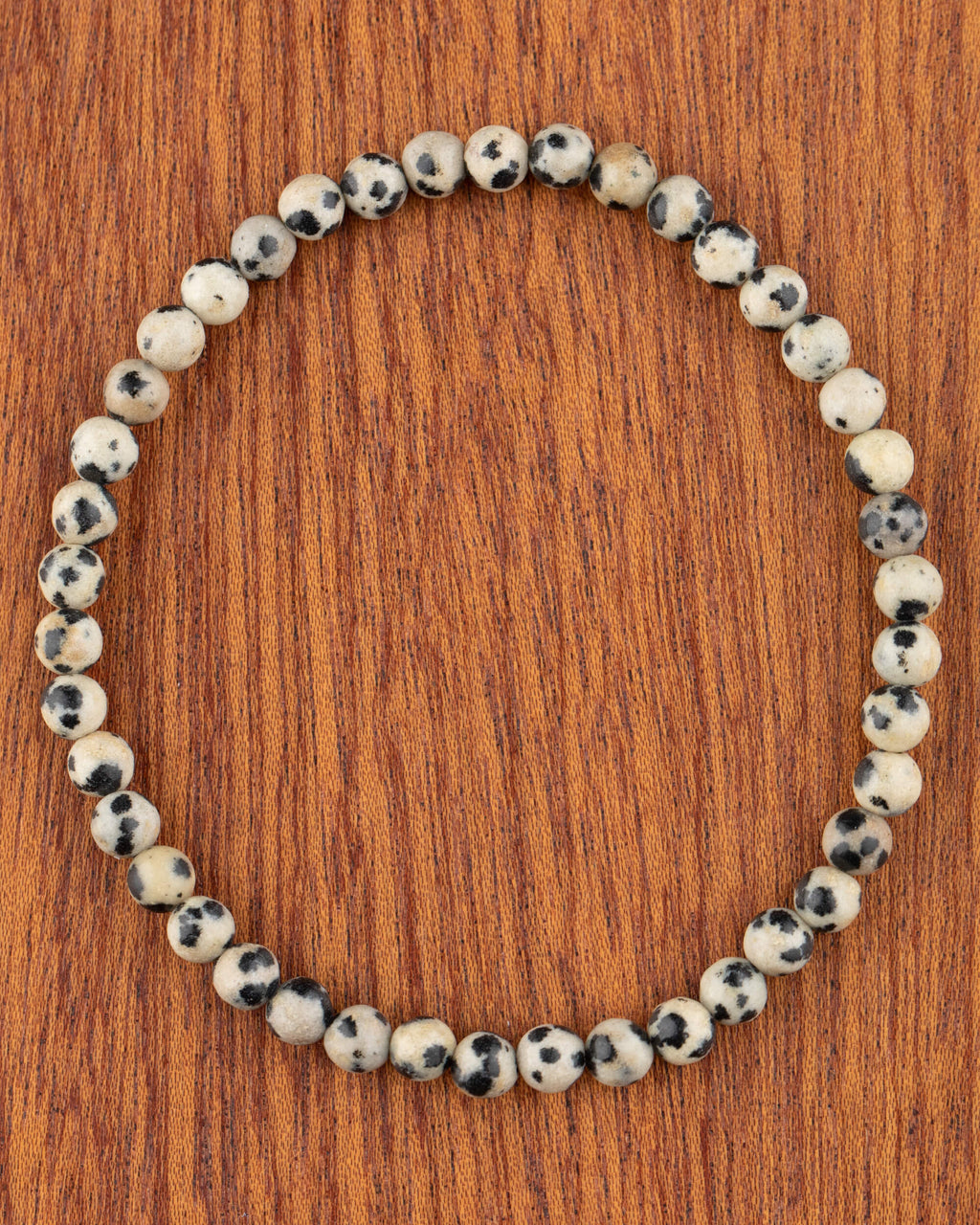 Pulsera de Jaspe Dálmata de 4 mm, pieza completa en círculo sobre madera