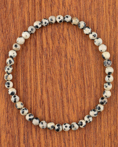Pulsera de Jaspe Dálmata de 4 mm, pieza completa en círculo sobre madera