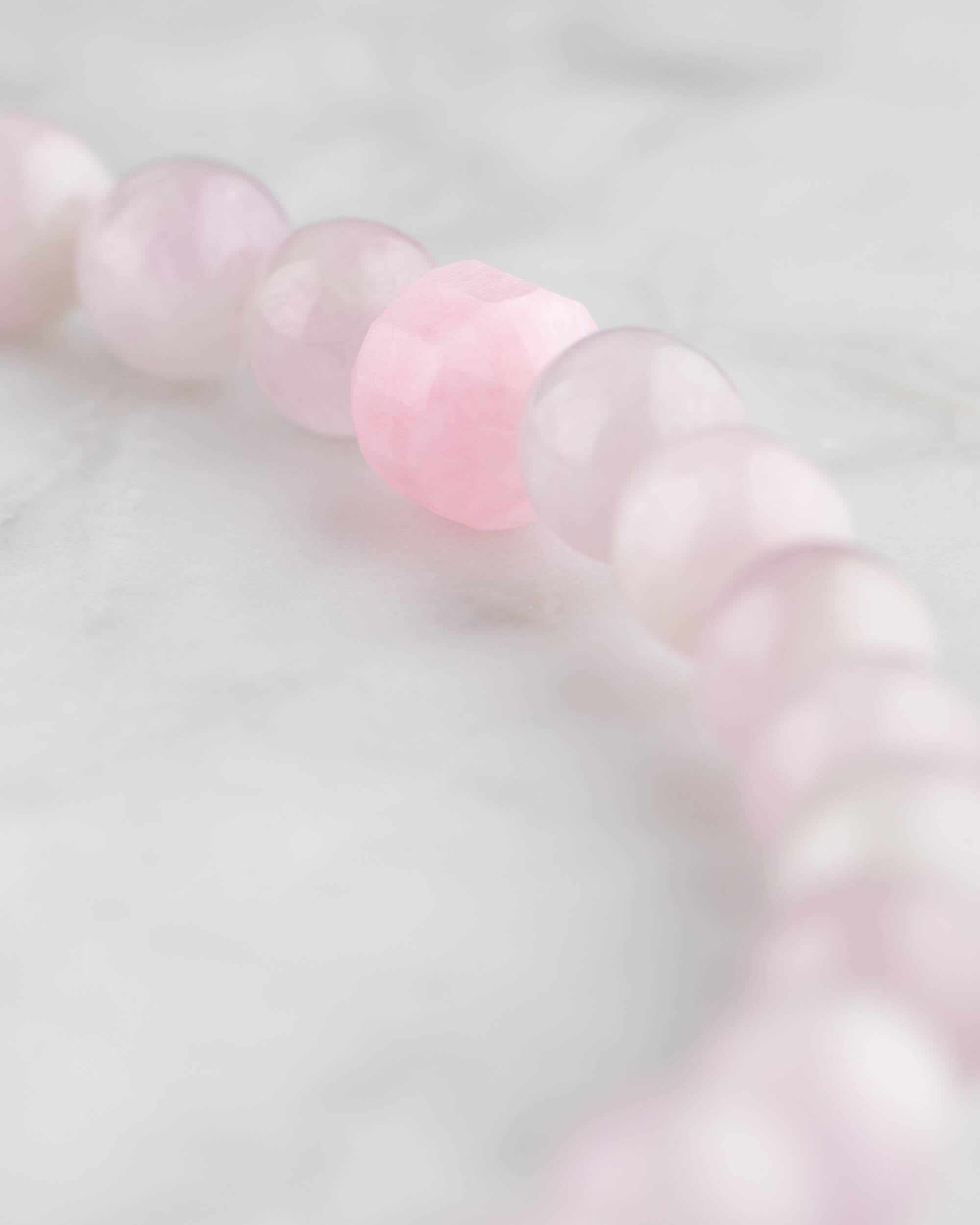Detalle macro de las cuentas de Kunzita con una cuenta facetada rosa intenso
