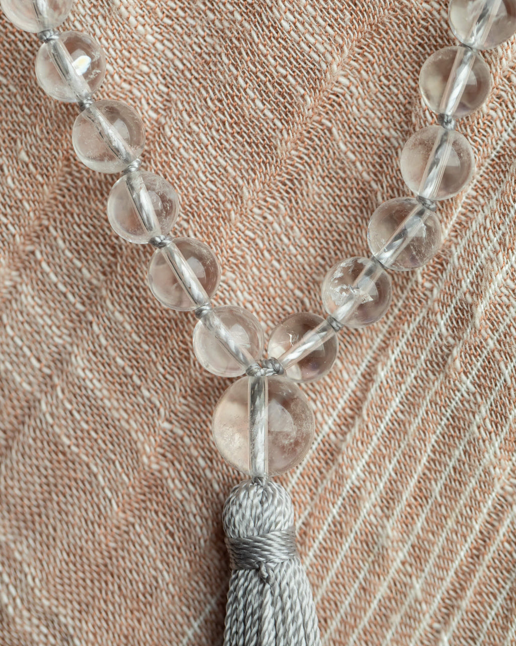 Japa Mala de Cuarzo Transparente con borla gris sobre tela clara