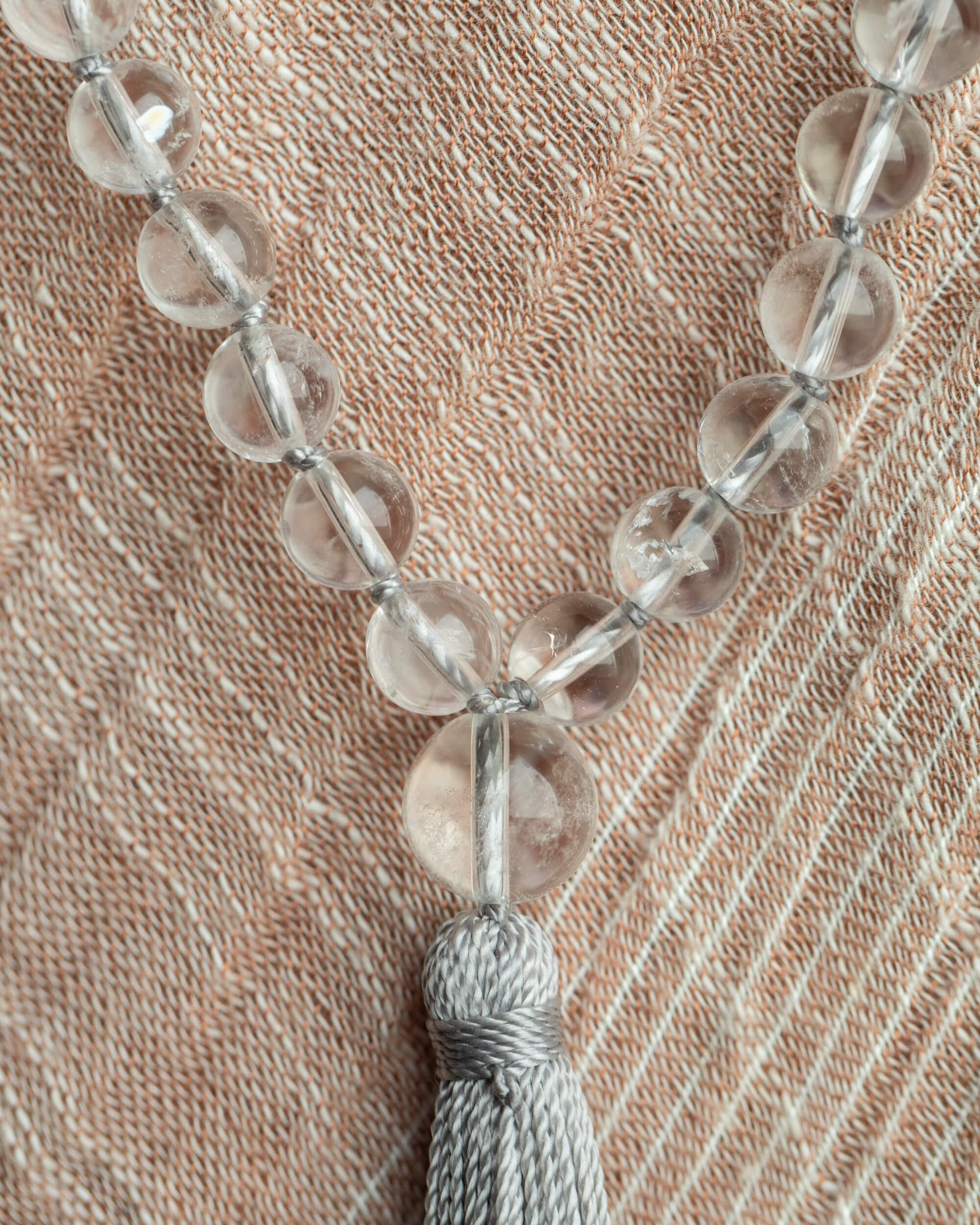 Japa Mala de Cuarzo Transparente con borla gris sobre tela clara