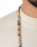 Detalle macro del collar de Ágata Mexicana en tonos beige y naranja, puesto sobre el cuello
