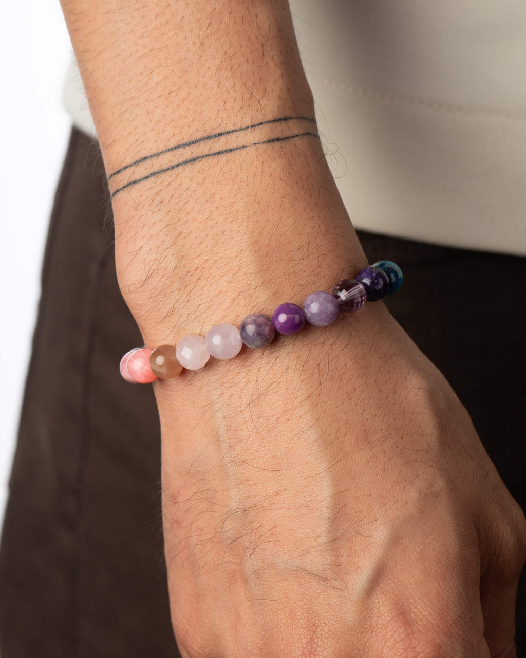 Pulsera 7 Chakras puesta en la muñeca, tonos rosas y violeta visibles
