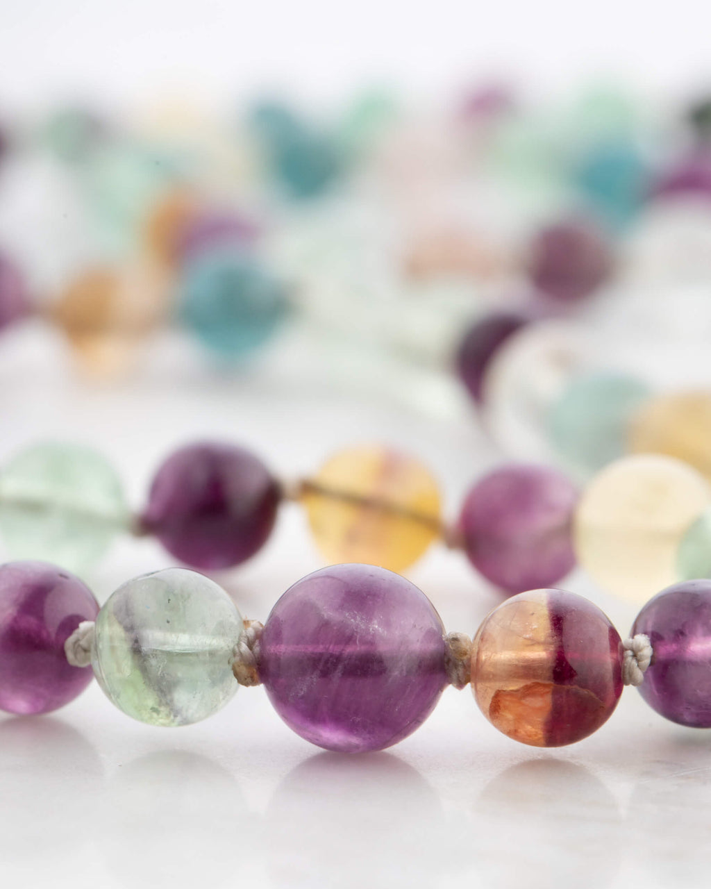 Detalle macro de las cuentas de Fluorita Arcoíris en tonos morado y ámbar