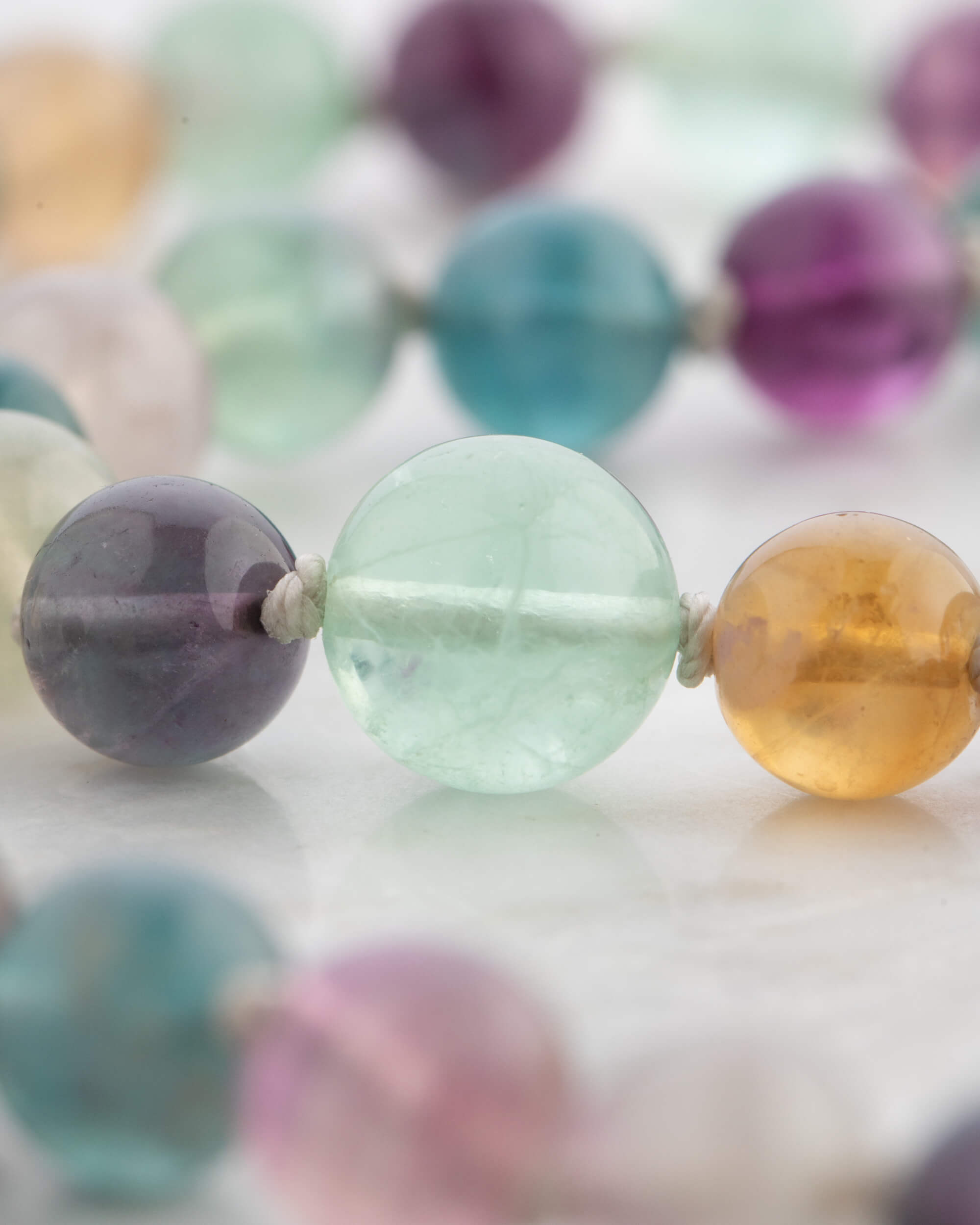 Detalle macro de las cuentas de Fluorita Arcoíris en tonos verde, morado y ámbar