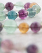 Detalle macro de las cuentas de Fluorita Arcoíris con tonos morado y azul cercanos
