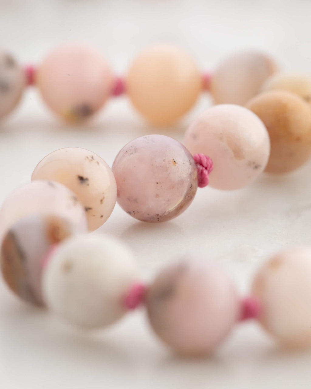 Detalle macro del nudo de Rodonita entre cuentas de Ópalo Rosa