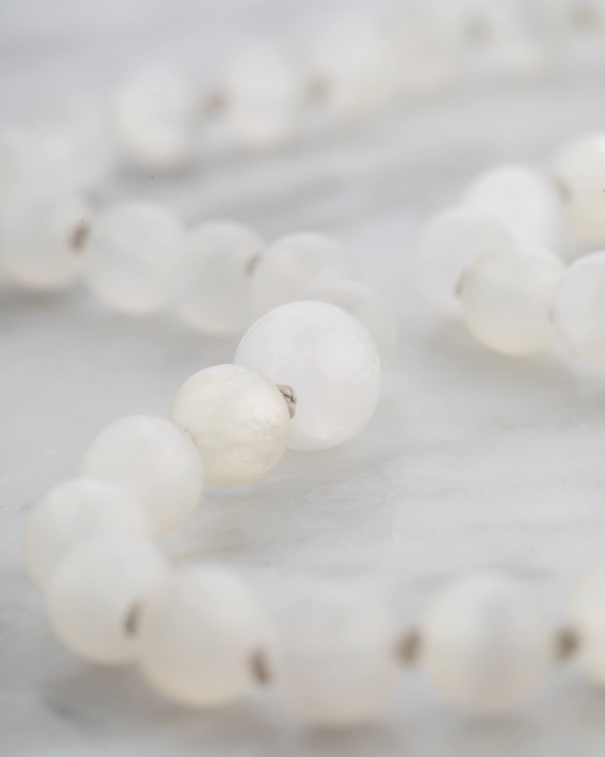 Detalle macro de las cuentas de Selenita, luz suave entre vueltas entrelazadas