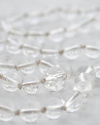 Detalle macro de las cuentas facetadas de Cuarzo Transparente sobre mármol