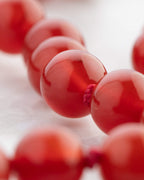 Detalle macro de una cuenta de Cornalina con nudo de hilo rojo
