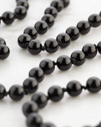 Detalle macro de la cuenta facetada de Turmalina Negra sobre mármol