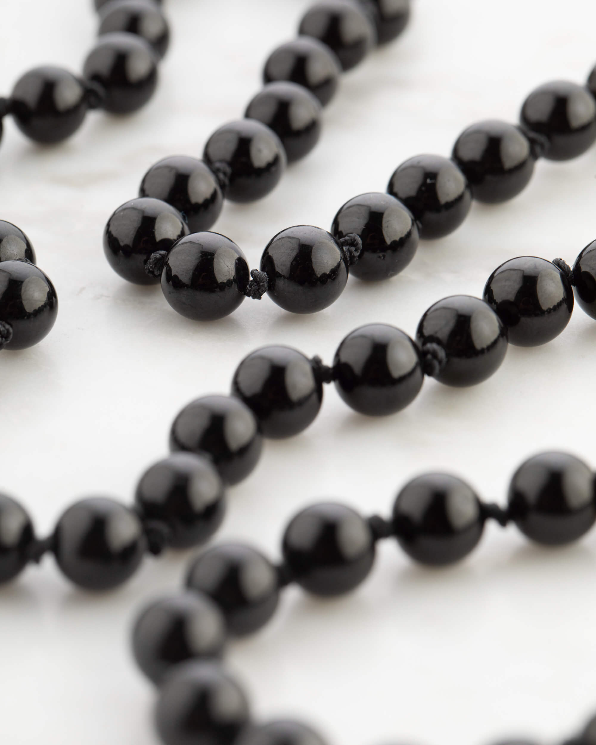 Detalle macro de la cuenta facetada de Turmalina Negra sobre mármol