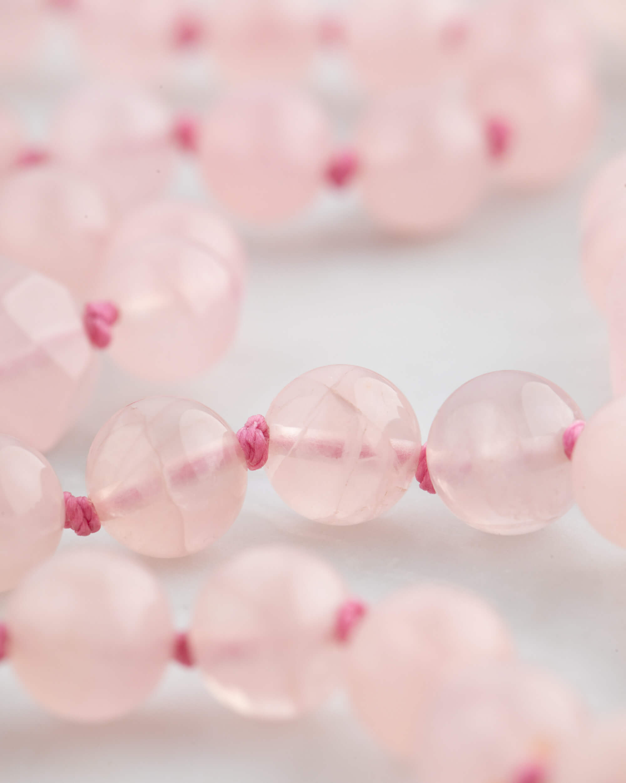 Detalle macro de las cuentas de Cuarzo Rosa con nudo fucsia entre ellas