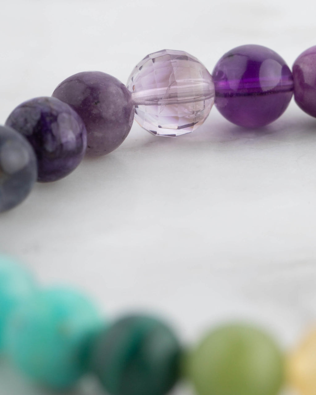 Detalle macro de cuentas moradas y violeta, una facetada y transparente, de la Pulsera 7 Chakras