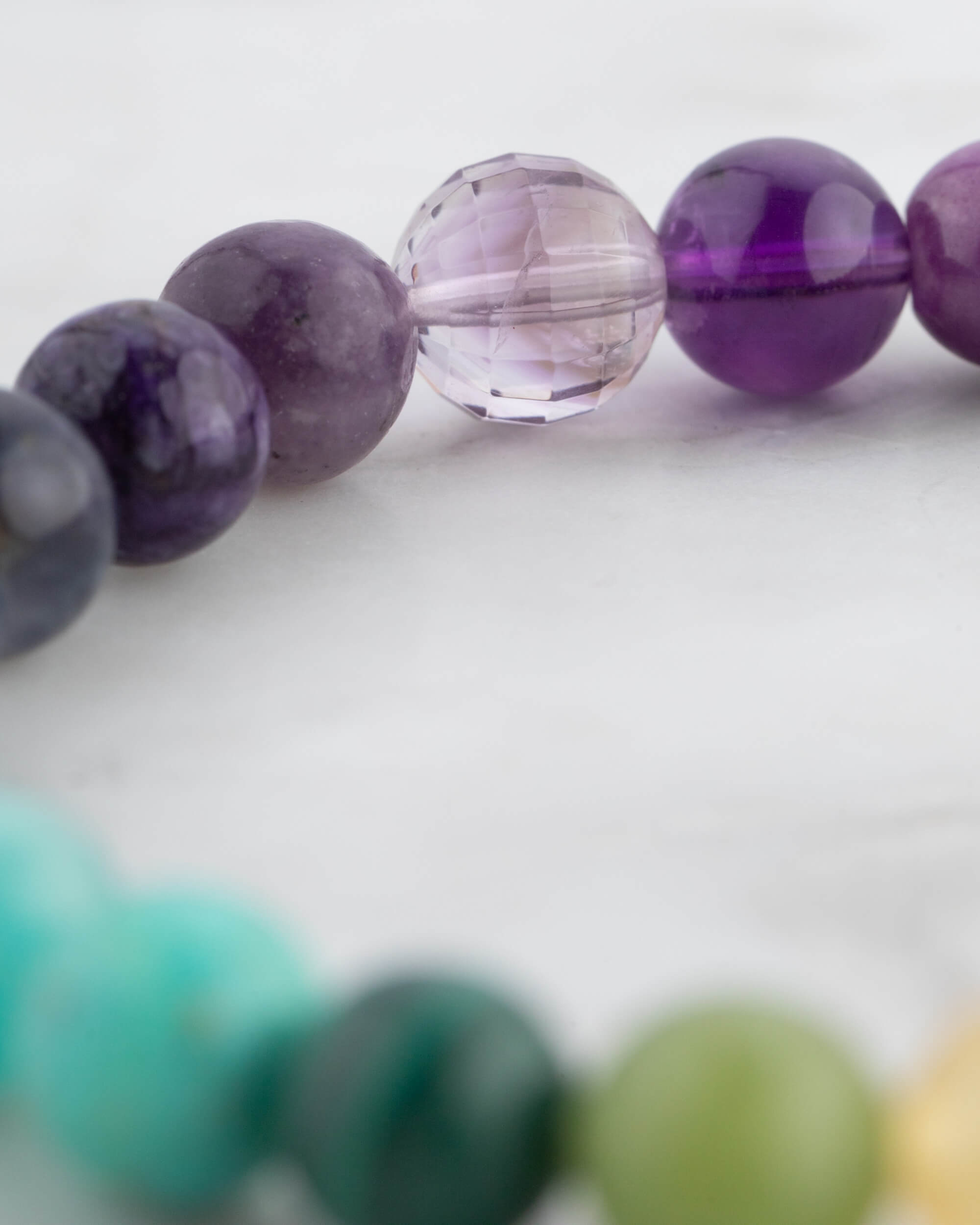 Detalle macro de cuentas moradas y violeta, una facetada y transparente, de la Pulsera 7 Chakras