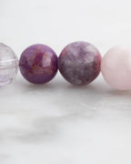 Pulsera 7 Chakras puesta en la muñeca, tonos rosas y morados de cerca