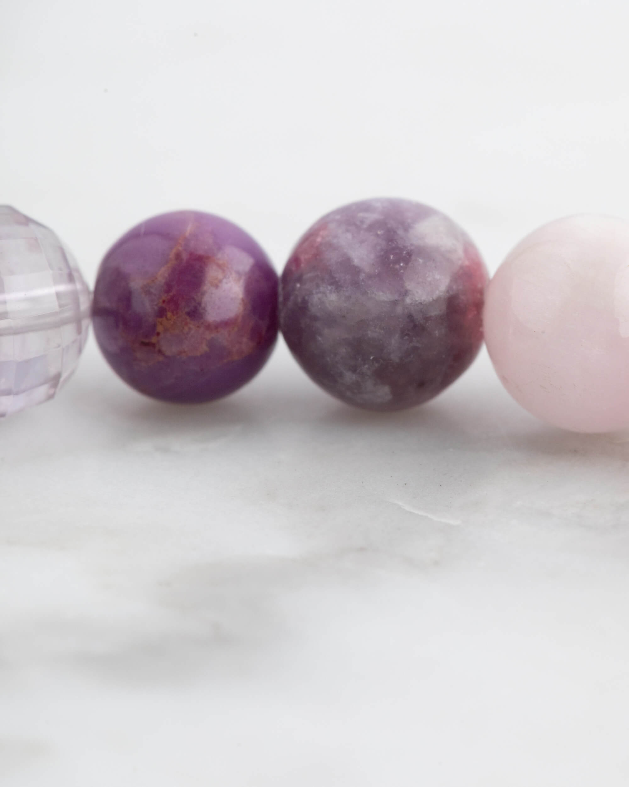 Pulsera 7 Chakras puesta en la muñeca, tonos rosas y morados de cerca