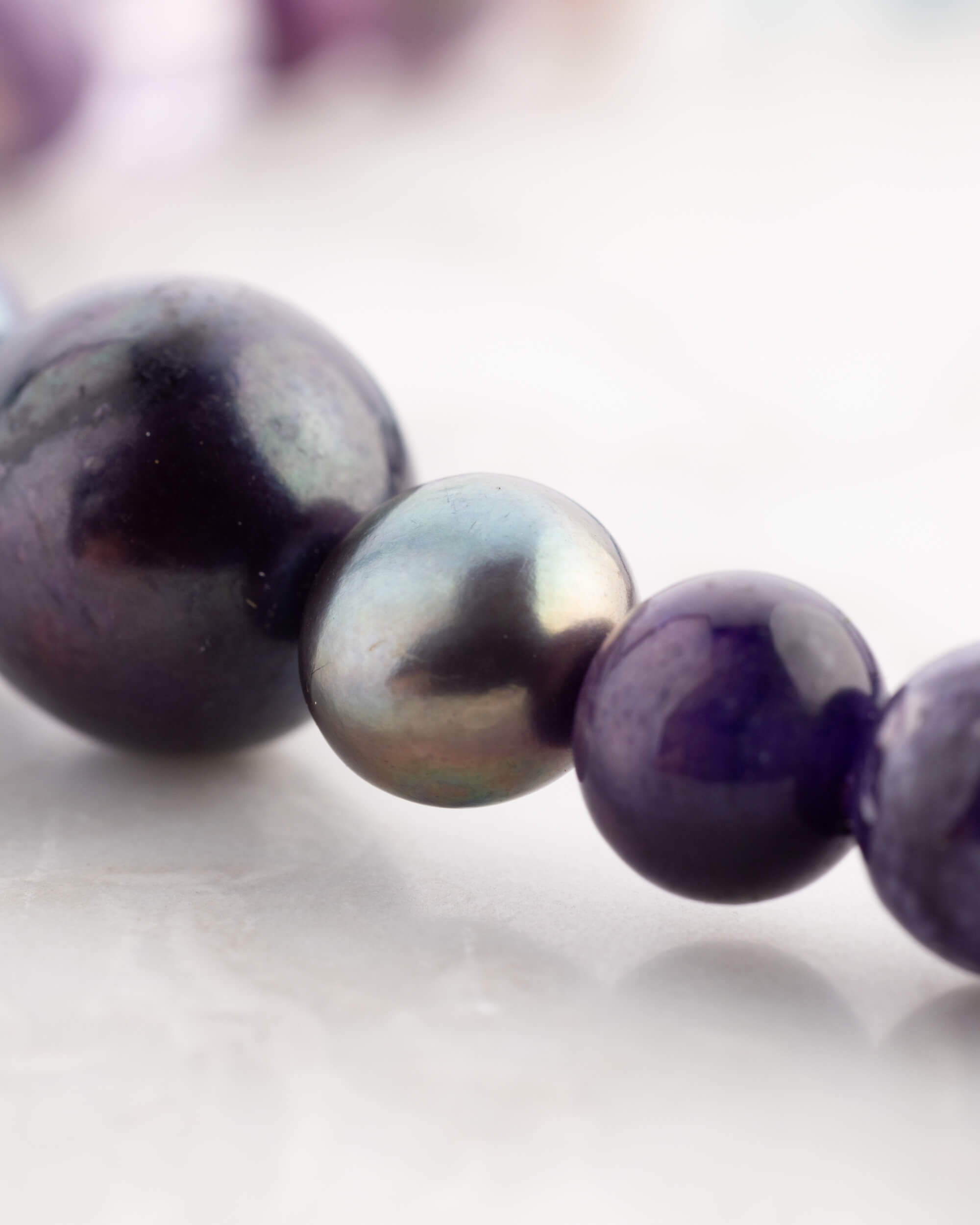 Detalle macro de perlas barrocas negras y Amatista del Codificador Universo