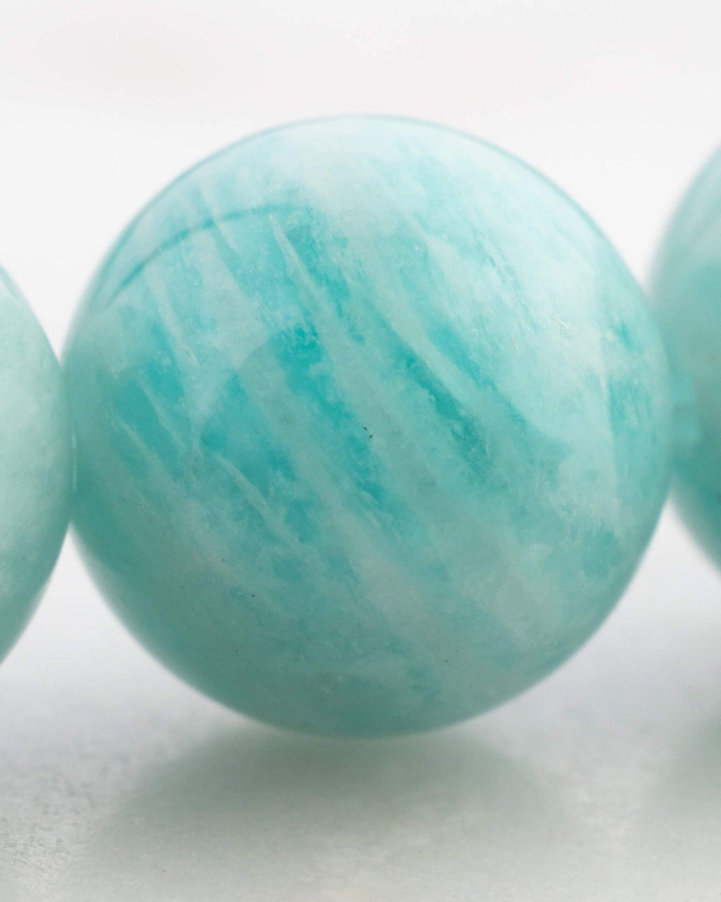 Detalle macro de una cuenta de Amazonita Aqua con vetas blancas y azul verdoso