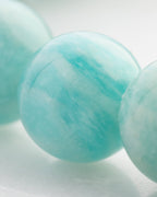 Detalle macro de una cuenta de Amazonita Aqua con vetas blancas entre otras cuentas