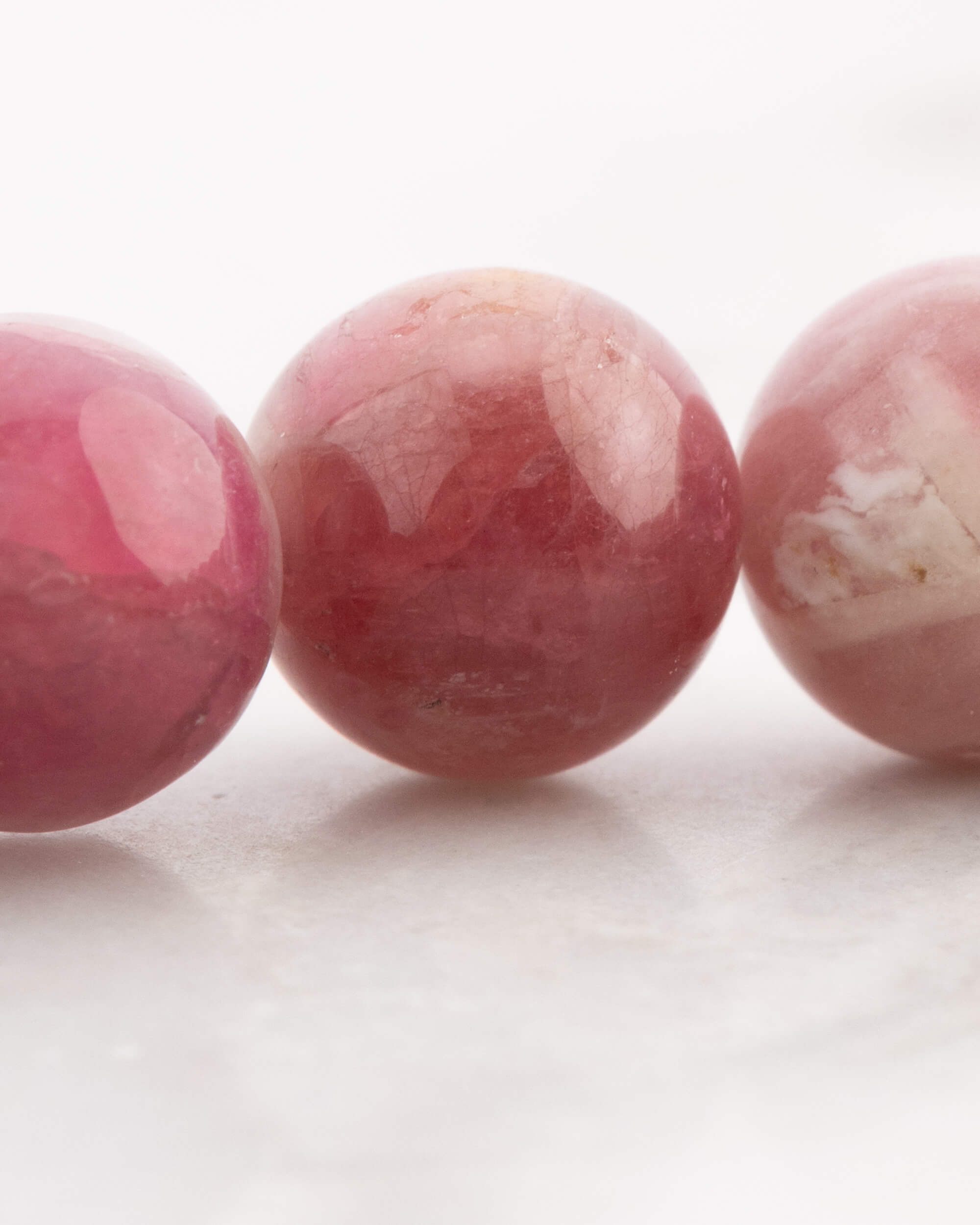 Detalle macro de las cuentas de Turmalina Rosa con vetas blancas, en fila junto a otras cuentas