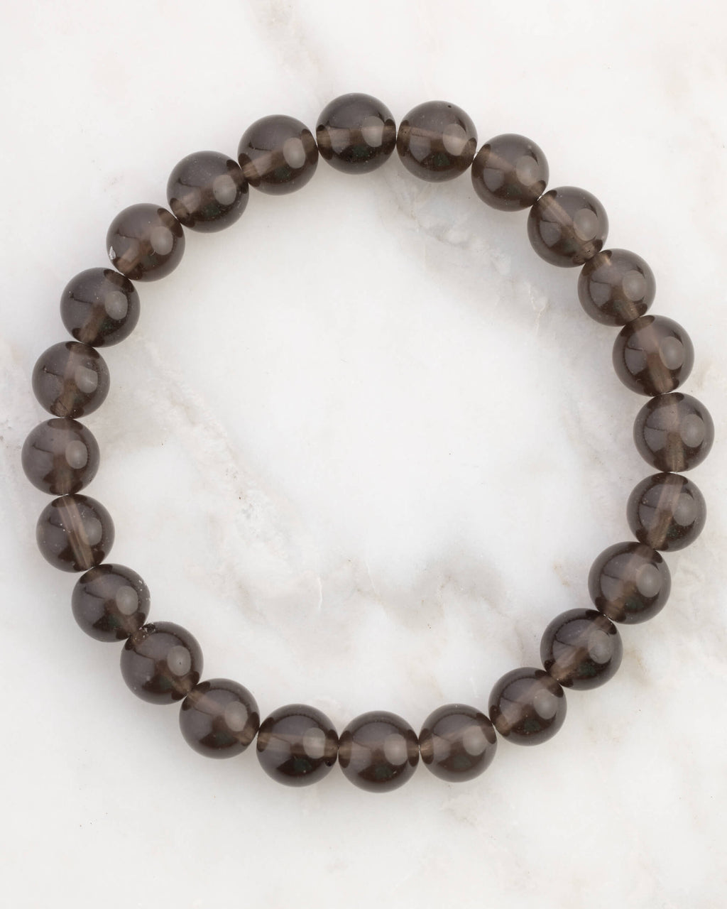 Pulsera de Saffordita de 8 mm, pieza completa en círculo sobre superficie de mármol claro