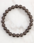 Pulsera de Saffordita de 8 mm, pieza completa en círculo sobre superficie de mármol claro