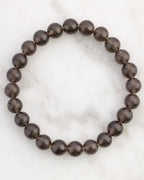 Pulsera de Saffordita de 8 mm, pieza completa en círculo sobre superficie de mármol claro