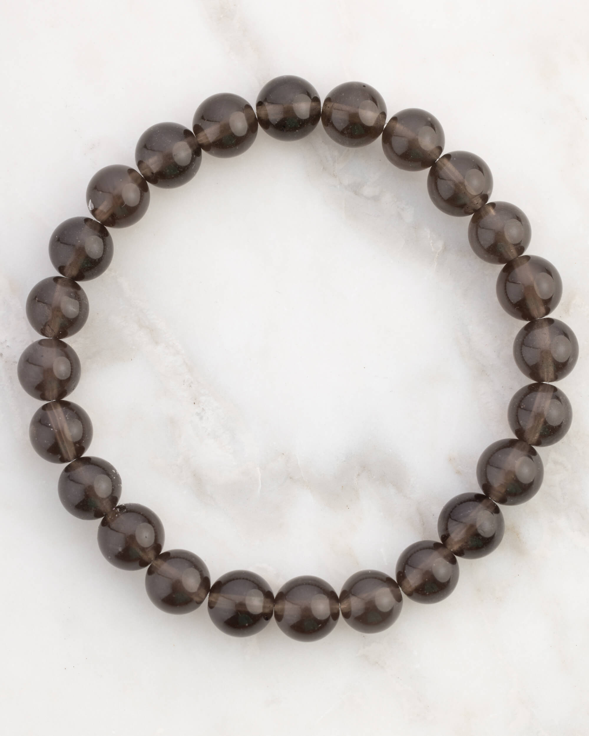 Pulsera de Saffordita de 8 mm, pieza completa en círculo sobre superficie de mármol claro