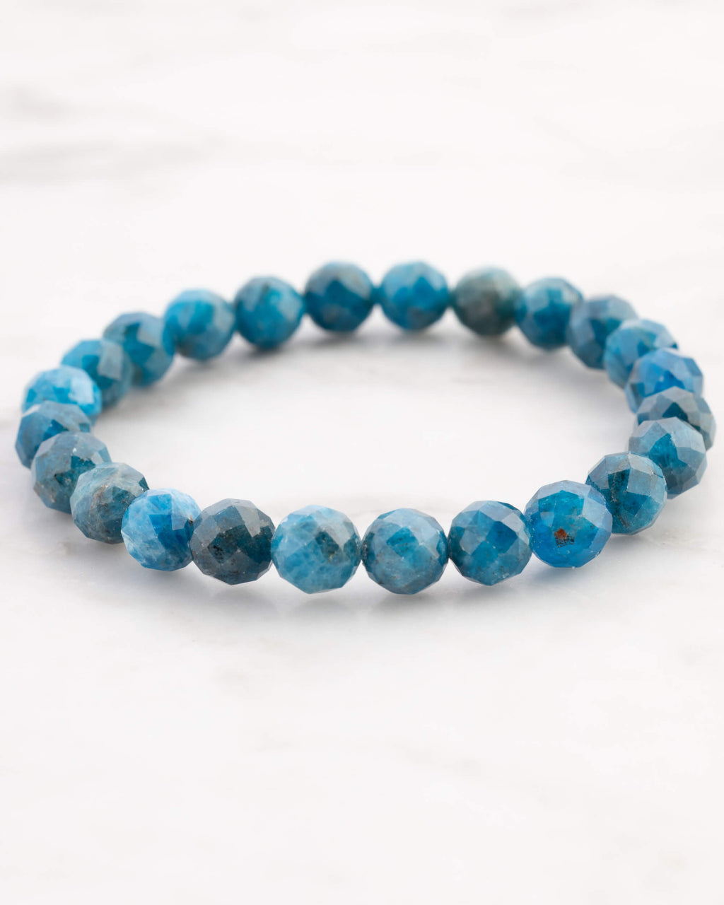 Pulsera de Apatita Azul facetada, pieza completa en ángulo distinto sobre mármol claro