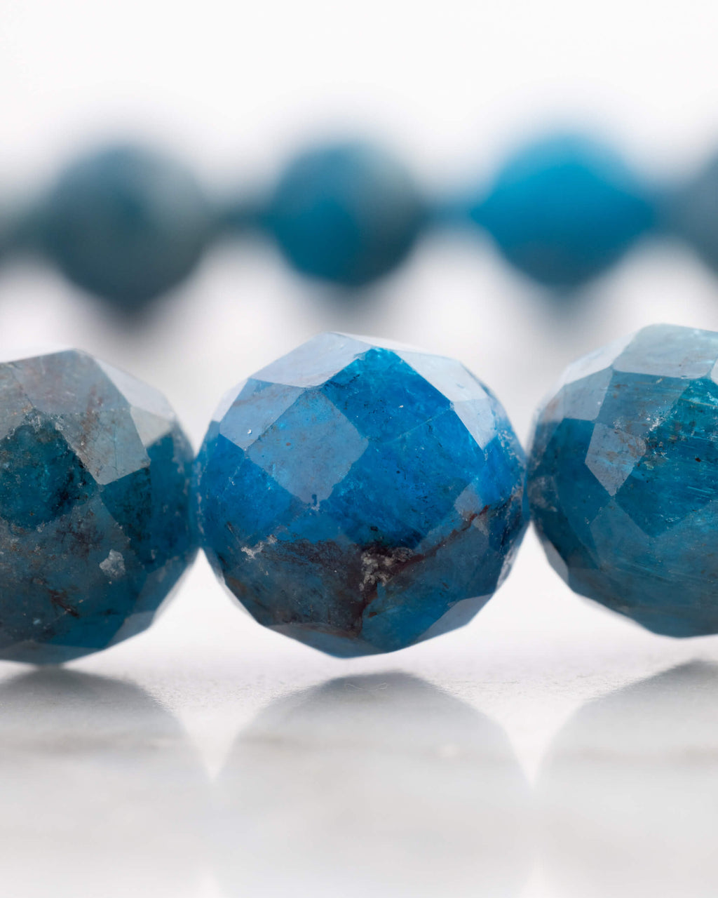 Detalle macro de las cuentas facetadas de Apatita Azul con vetas cobrizas visibles