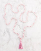 Japa Mala de Cuarzo Rosa extendido en forma de S sobre superficie de mármol