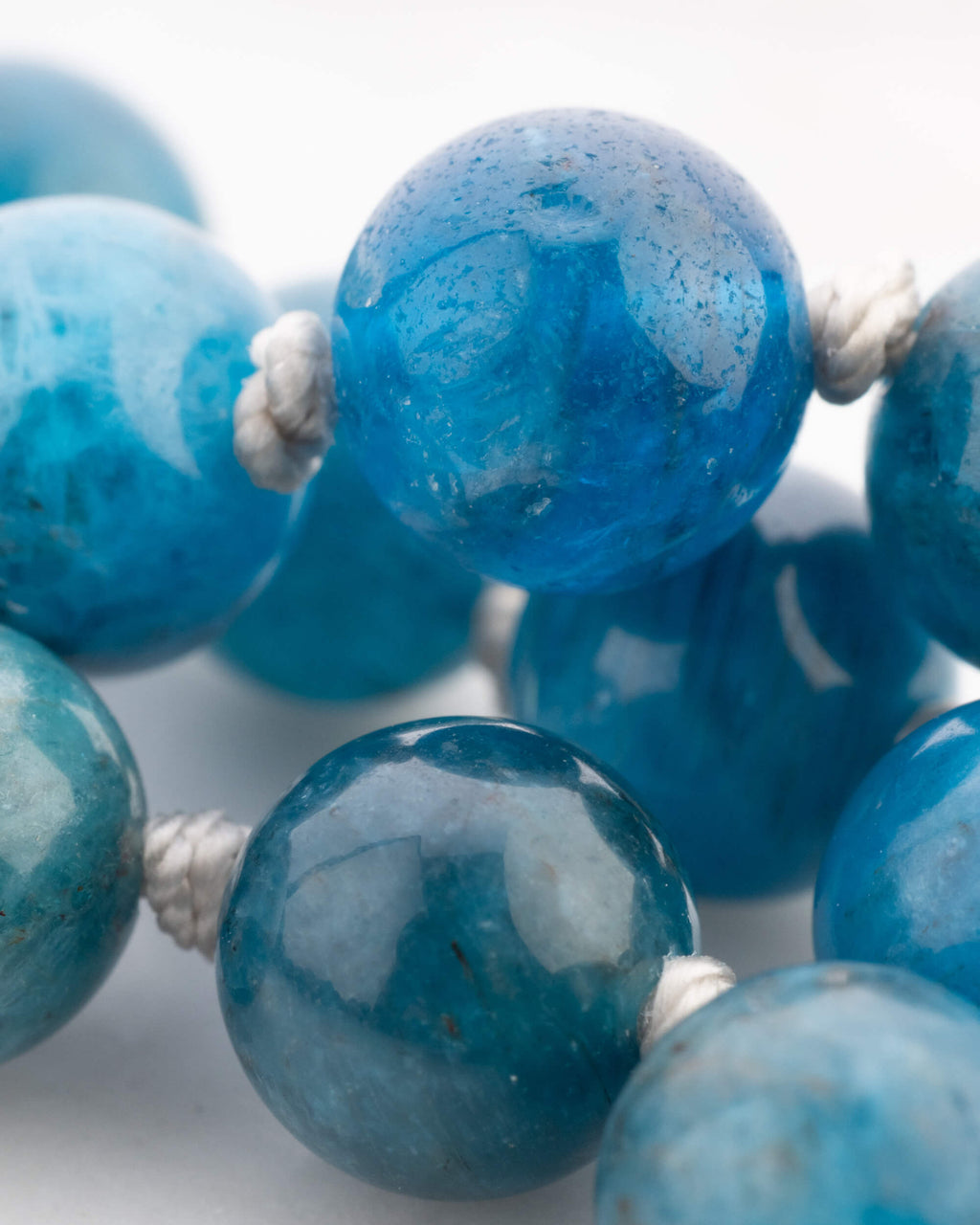 Detalle macro de cuentas de Apatita Azul con vetas blancas y nudos
