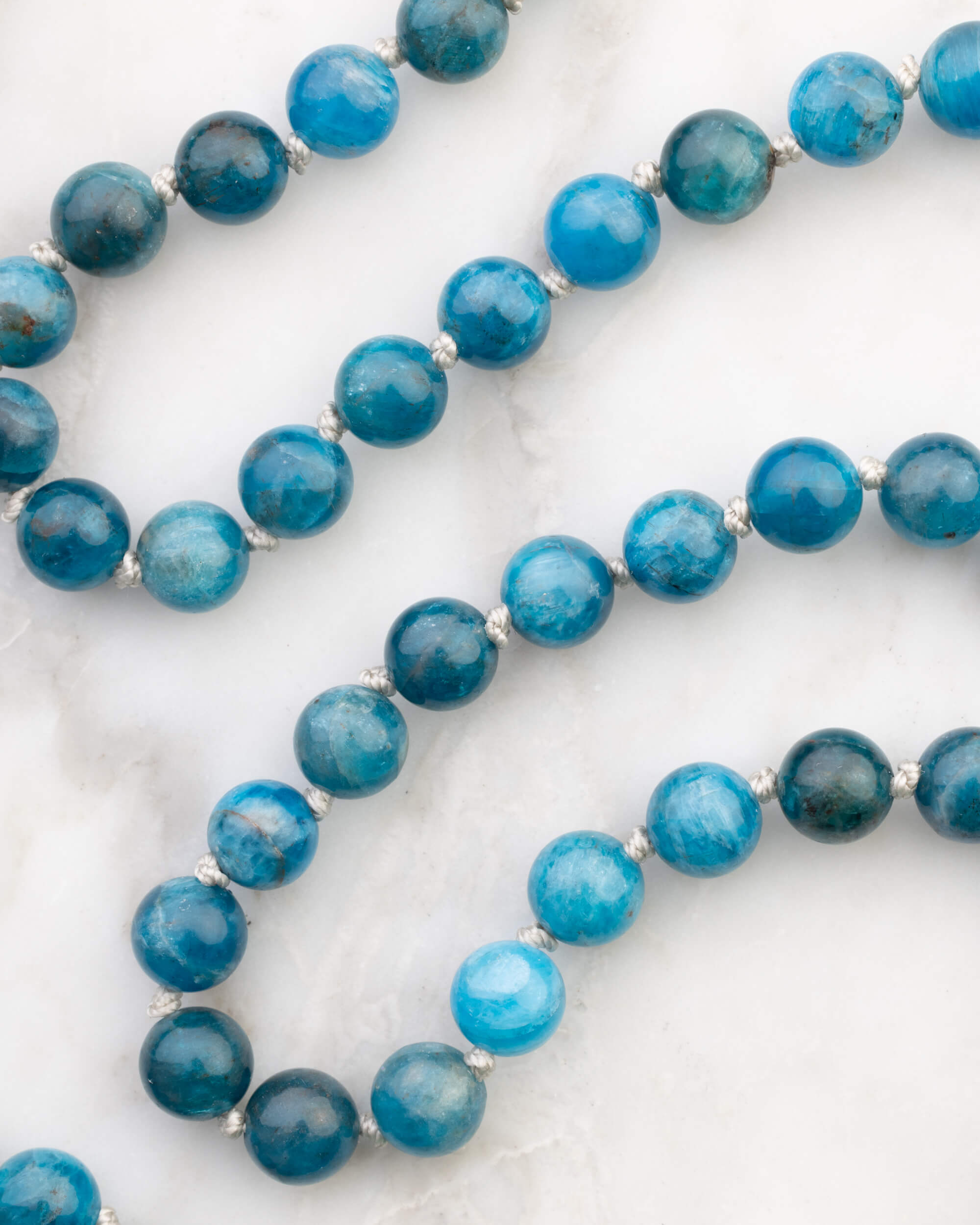 Japa Mala de Apatita Azul completo, extendido sobre playera clara con borla