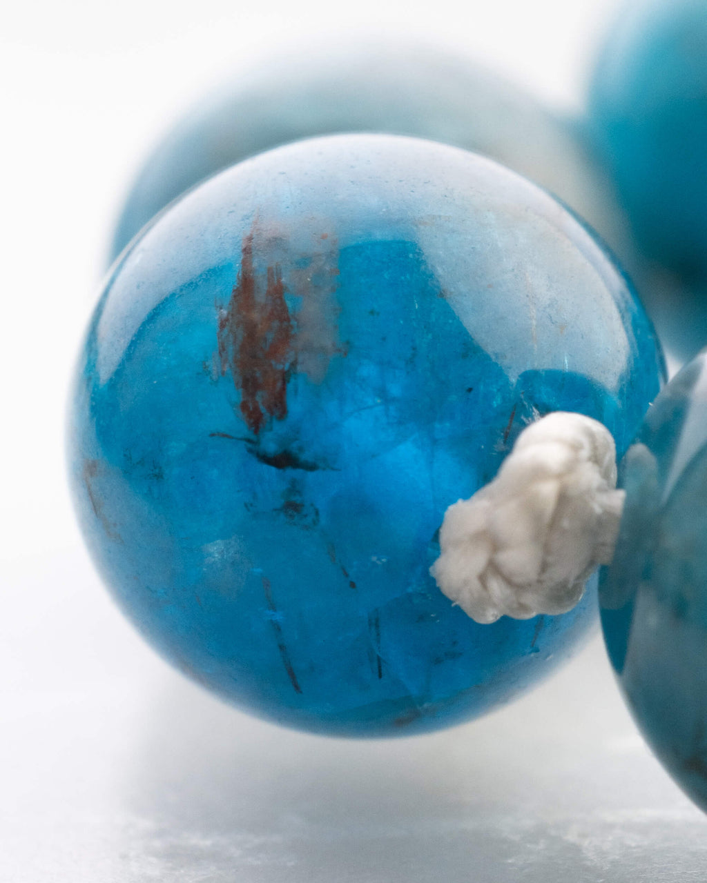 Detalle macro de cuentas de Apatita Azul con nudo de algodon en primer plano