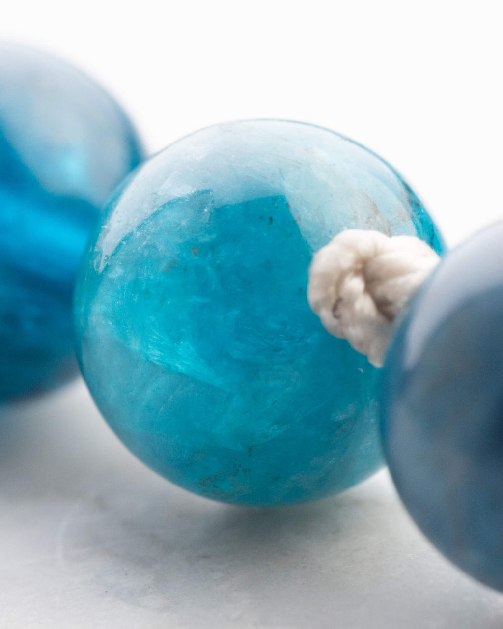 Primer plano de una cuenta de Apatita Azul con nudo de algodon claro