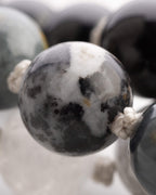 Detalle macro de una cuenta moteada gris y blanca junto a cuentas negras desenfocadas
