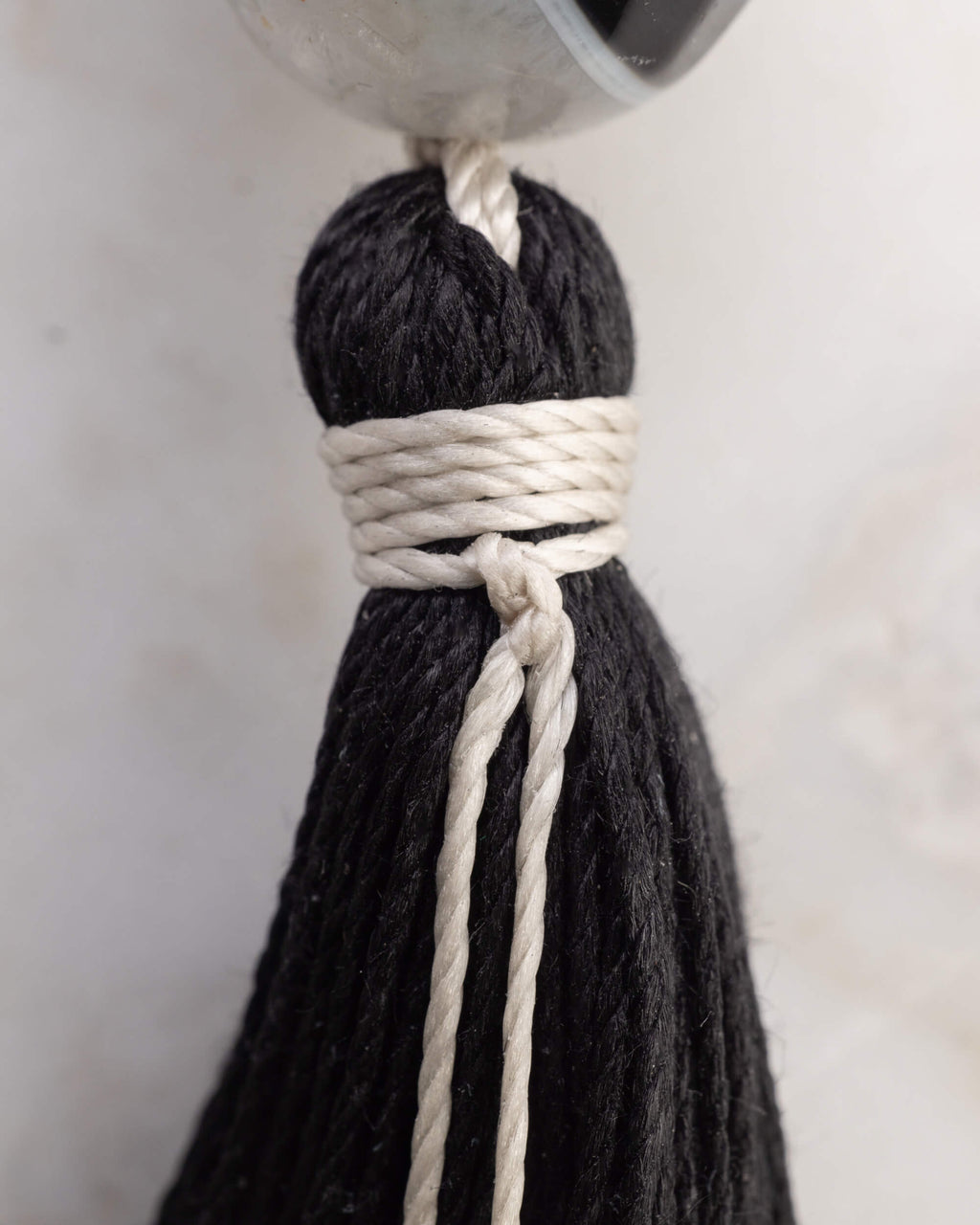 Detalle macro de la borla negra tejida del Japa Mala Dualidad con hilo blanco