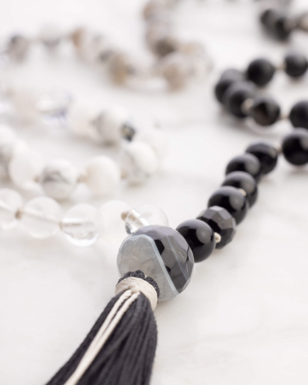 Pulseras del Japa Mala Dualidad en tonos blanco, gris y negro sobre mármol