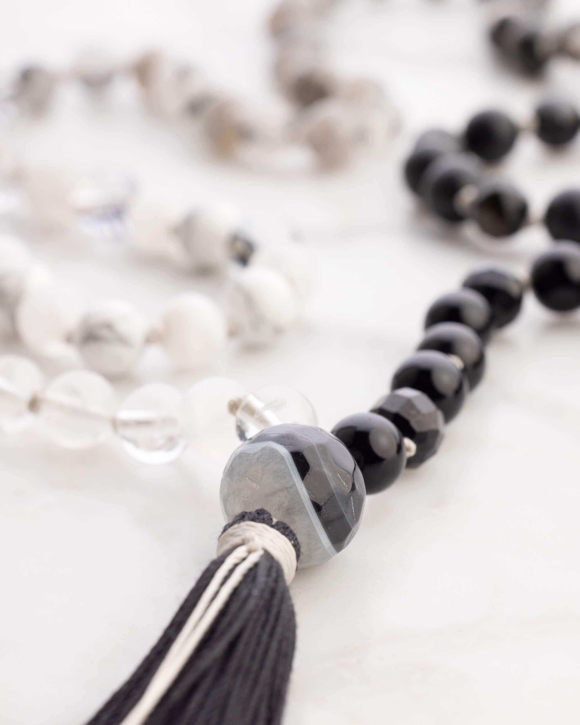 Pulseras del Japa Mala Dualidad en tonos blanco, gris y negro sobre mármol