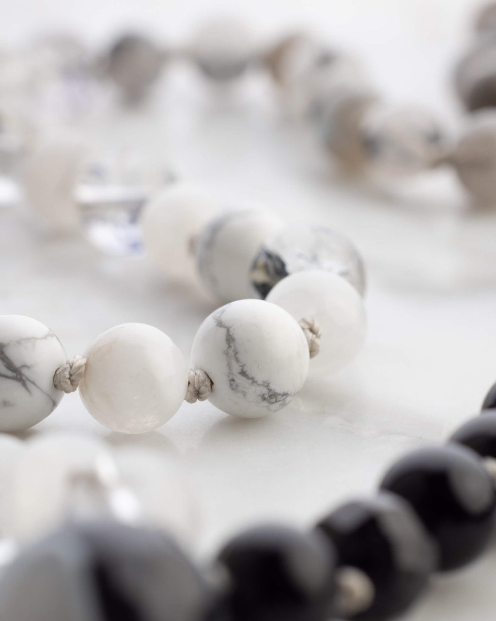 Detalle macro de cuentas de Howlita blanca y Obsidiana Negra en degradado